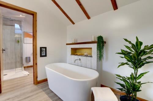 uma banheira branca numa casa de banho com uma planta em The Owl Barn Wiltshire - Flint em Swindon