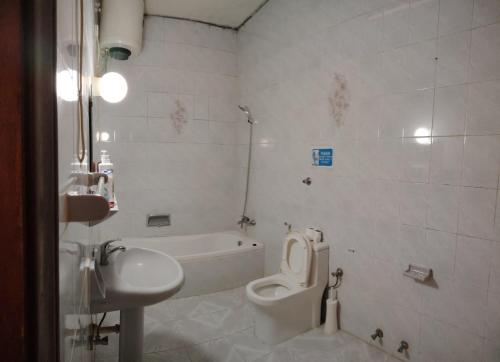 a white bathroom with a toilet and a sink at Bzxmax Guest House in Al Ain