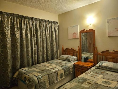 a bedroom with two twin beds and a mirror at Stella Maris 118 in Amanzimtoti