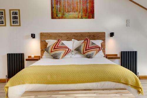 um quarto com uma cama grande e um cobertor amarelo em The Owl Barn Wiltshire - Flint em Swindon