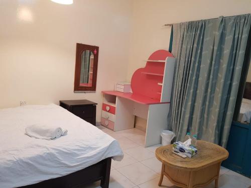 a bedroom with a bed and a desk and a mirror at Bzxmax Guest House in Al Ain