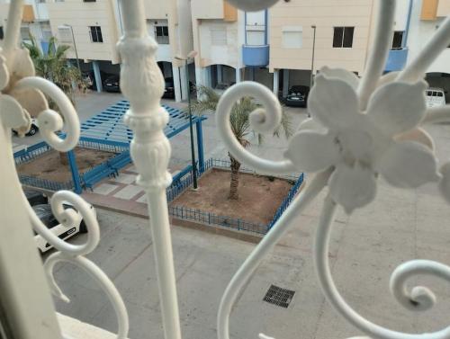 une clôture blanche avec un palmier dans un parking dans l'établissement Appartement Agadir, à Agadir