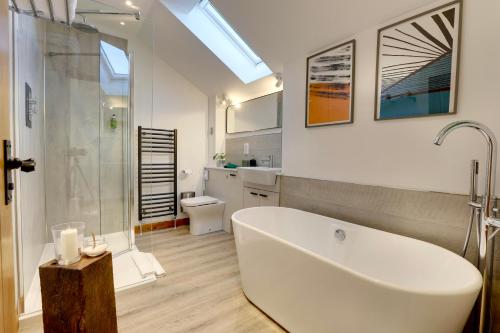 a bathroom with a large white tub and a shower at The Owl Barn Wiltshire - Slate in Swindon