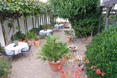 a patio with tables and chairs and potted plants at Hotel Linde in Speyer