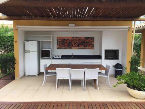 een patio met een tafel en stoelen en een koelkast bij Quintas de Sauipe - modernes Haus im Condomínio mit Service in Mata de Sao Joao