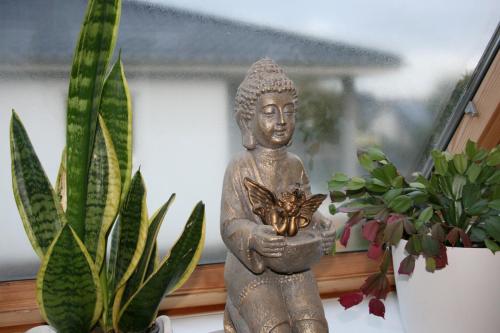een standbeeld van een Boeddha met een vlinder bij Ferien Oase am BER in Schönefeld