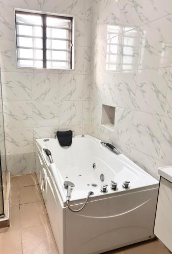 uma banheira branca na casa de banho com paredes em mármore branco em Luxury 4 bedroom shared shortlet apartment lekki em Lagos