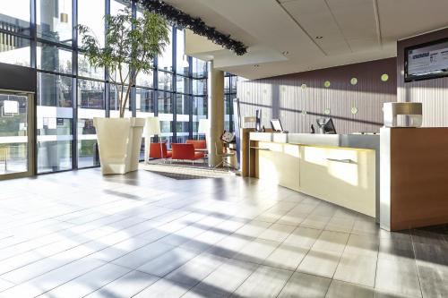 an office lobby with a reception desk and windows at Novotel Edinburgh Park in Edinburgh