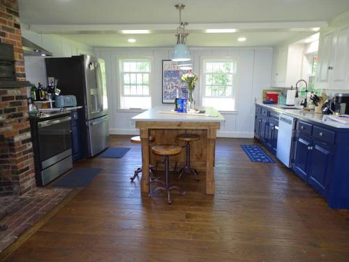a kitchen with blue cabinets and a island in the middle at Lookout at Pleasant Bay with a private beach in Orleans