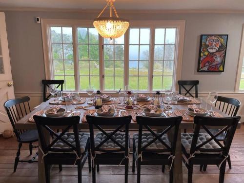 a dining room table with chairs and a chandelier at Lookout at Pleasant Bay with a private beach in Orleans