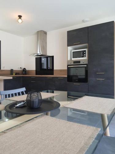 une cuisine avec des placards noirs et une table avec un four micro-ondes dans l'établissement Villa Montélimar, à Montélimar