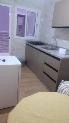 eine Küche mit einer Theke, einem Waschbecken und einem Fenster in der Unterkunft New Rif Appartement Appelle moi 07 et 74 et 41 et 16 et 91 in Al Hoceïma