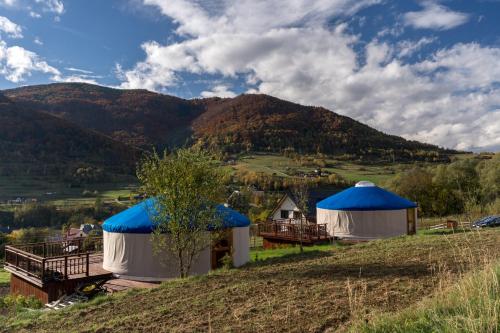 GÓRSKI GLAMPING - Całoroczne jurty z widokiem في Tylmanowa: مجموعة من الخيام على تلة مع جبل