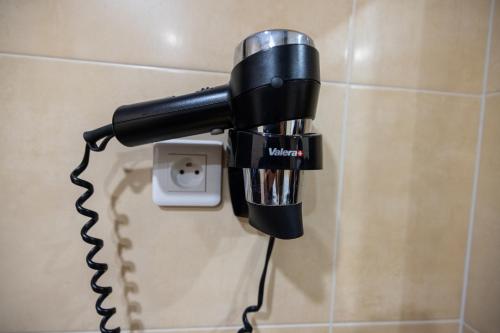 a black blow dryer plugged into a socket at Lalla Doudja Hotel in Alger