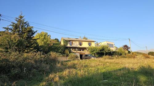 a house sitting on a hill in a field at Le Panoramique du Plongeoir - T4 spacieux de 90m2 avec grande terrasse vue sur le lac de Serre Ponçon in Savines
