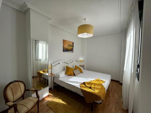 una camera con un letto bianco e due sedie di El paraíso de Lita - a 10 min del centro con WiFi a Oviedo