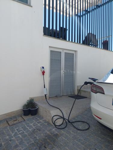 a car is parked next to a wall with a hose at Al Santiago T2 in Castelo do Neiva