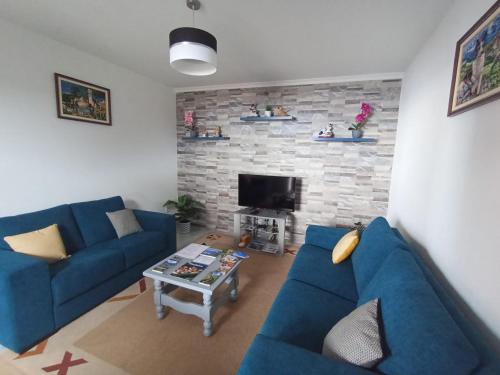 a living room with two blue couches and a fireplace at Casa dos Avós Domingos & Matilde in Estreito da Calheta