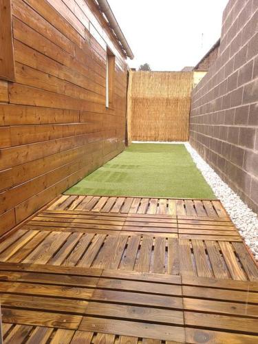 un patio en bois avec une pelouse verdoyante dans un bâtiment dans l'établissement T2 cosy et calme avec terrasse, à Tourcoing
