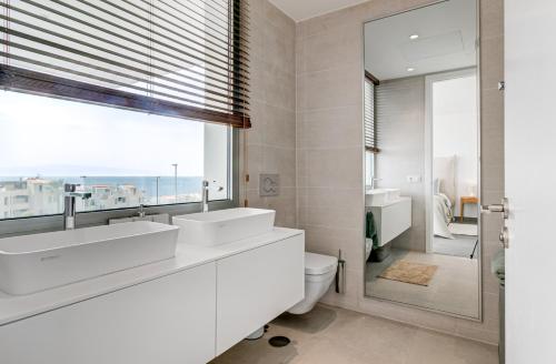 Un baño con dos lavabos y un inodoro y una ventana. en Villa Izabele Orange, en Callao Salvaje