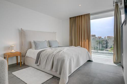 a white bedroom with a bed and a large window at Villa Izabele - private heated pool with amazing terrace in Callao Salvaje