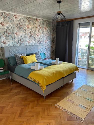 a bedroom with a large bed with a yellow blanket at Moderne Wohnung mit 2 Balkonen, Self check-in, Parking in Graz