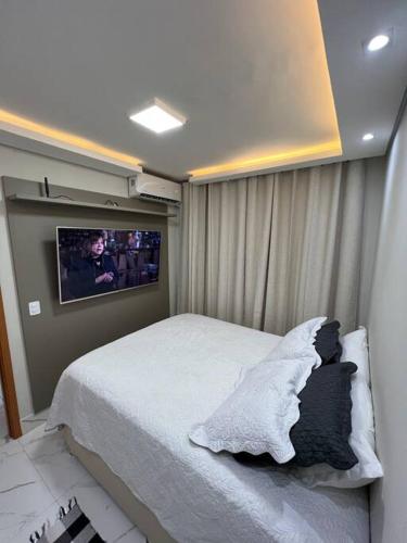 a bedroom with a bed and a tv on the wall at Lindo apartamento em Cuiabá in Cuiabá