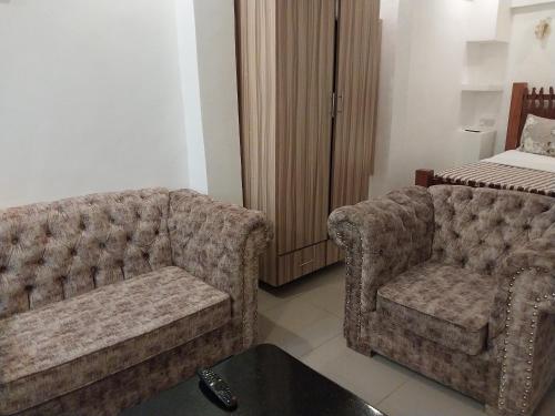 a living room with two chairs and a bed at Downtown Penthouse in Eldoret