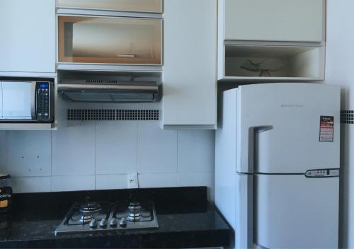 a white kitchen with a stove and a refrigerator at Elegância e Conforto no Centro da Cidade in Vespasiano