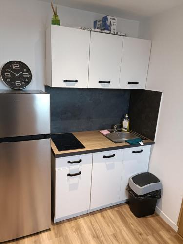 a kitchen with white cabinets and a stainless steel refrigerator at Studio confortable style in Roubaix