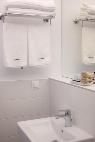 a white bathroom with a sink and towels at LOCATION in Sofia