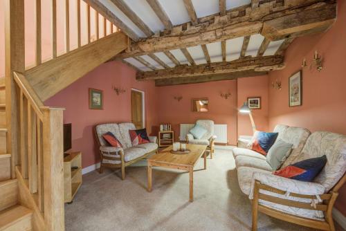 Historic cottage in the beautiful Wye Valley في Saint Briavels: غرفة معيشة مع عوارض خشبية وجدران وردية