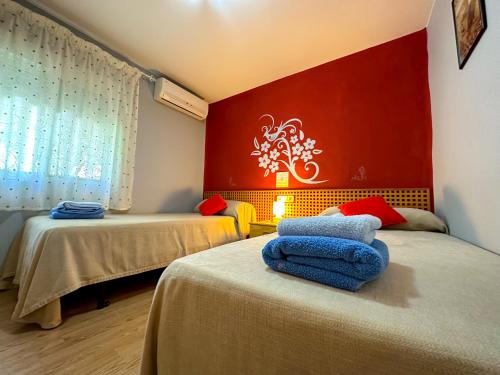 Cette chambre comprend 2 lits et un mur rouge. dans l'établissement Casa Rural Los Pinos, à Valmuel