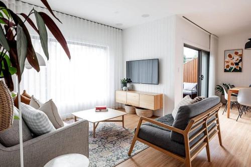 a living room with a couch and a tv at Convenient luxury home, minutes to CBD + hospital in Launceston