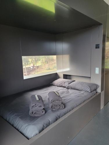 a bed with two towels on it with a window at the black line house in Olot