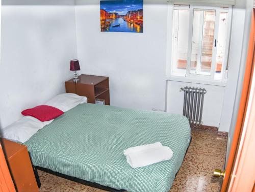 um pequeno quarto com uma cama verde e uma janela em LUCERO APARTAMENTO em Madri
