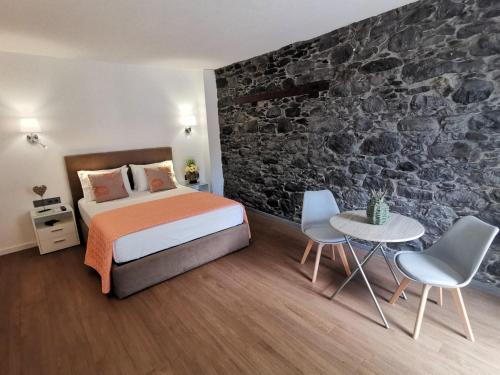 a bedroom with a bed and a stone wall at Chalé Esmeralda - Charming Studios in Calheta Beach in Calheta