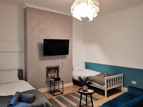 a living room with a couch and a tv on a wall at Bee Stays - Cooper House in Haydock