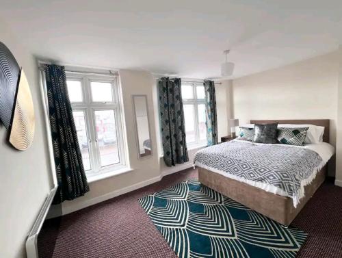 a bedroom with a bed and two windows and a rug at Taunton Flats in Taunton