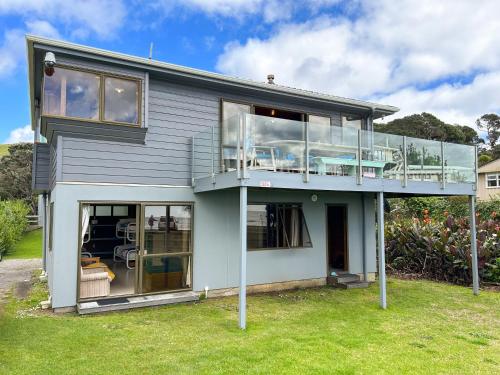 a house with glass windows and a balcony at Sandy Bay Beachfront in Matapouri
