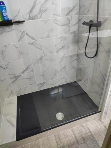 La salle de bains est pourvue d'une douche et de murs en marbre blanc. dans l'établissement Studio climatisé 50 m.du port, à Saint-Cyprien