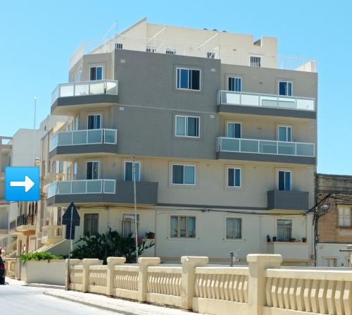 un edificio alto con una valla delante en "Joseph 2" Stylish corner flat with open views, just 5km from the beach, en Siġġiewi