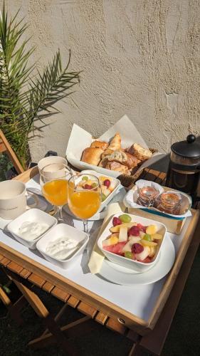 une table avec un plateau de nourriture et des verres de jus d'orange dans l'établissement Spa NESSA, à Saint-Andiol