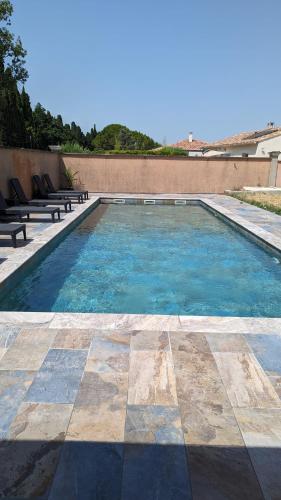 - une piscine avec bancs sur le côté d'un bâtiment dans l'établissement Spa NESSA, à Saint-Andiol
