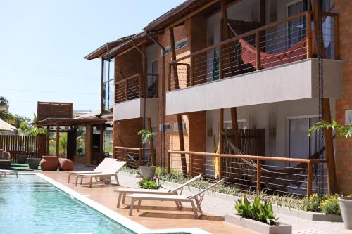 a resort with a pool and chairs and a building at Uri Pousada in Maragogi