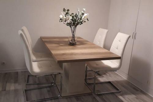 a table with white chairs and a vase of flowers at Apartamento acogedor in El Vendrell