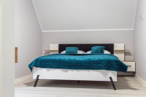 sypialnia z łóżkiem z niebieskimi kocami i poduszkami w obiekcie Domki na wzgórzu w Jamołtówku