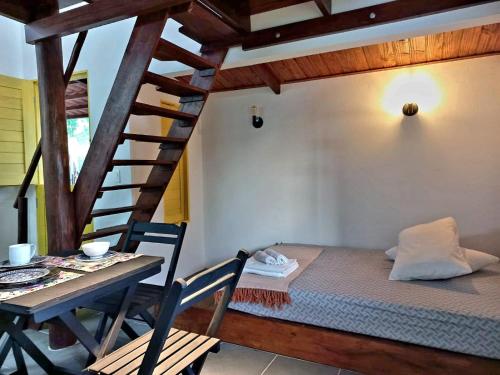 een kamer met een bed, een tafel en een trap bij Cumbeba Tiny Houses in São Miguel do Gostoso
