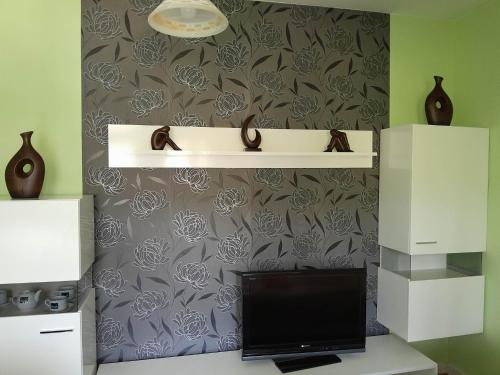 a desk with a monitor and a shelf on a wall at Willa Dniestrzanka in Krynica Zdrój