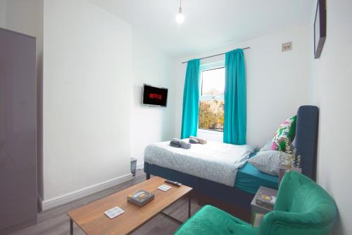 um quarto com uma cama e uma cadeira verde em Cosy family home w/Wi-Fi, parking, self check-in em Londres